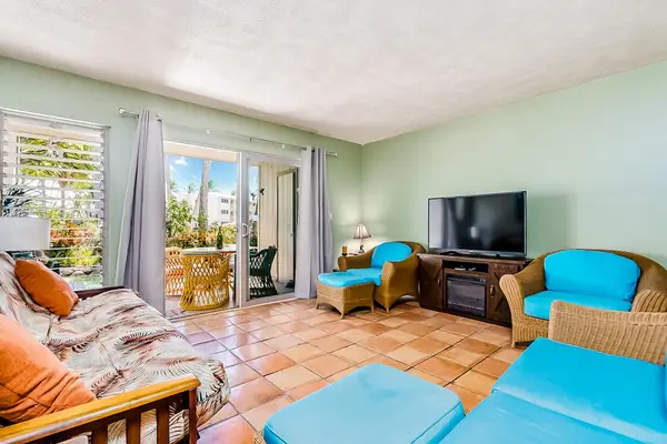 Inviting living room showcases turquoise chairs, television, and balcony sunlight