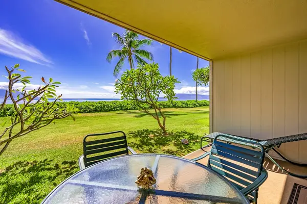 Covered patio offers dining with expansive lawn and ocean views
