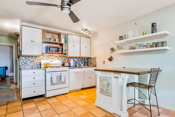 Full kitchen features island seating, open shelving, and modern appliances