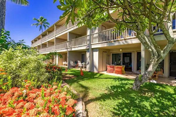 Resort building surrounded by gardens, palms, walkways, and green lawns