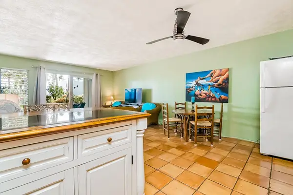 Kitchen island faces dining space beneath ceiling fan, with windows