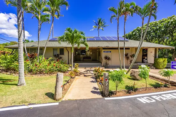 Resort entrance shows landscaped grounds, palm trees, parking, and accommodations