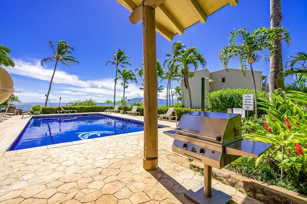 Barbecue area offers grill, ocean views, palms, and shaded shelter