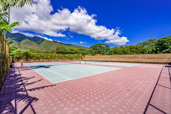 Resort tennis court sits beneath blue skies with mountain backdrop