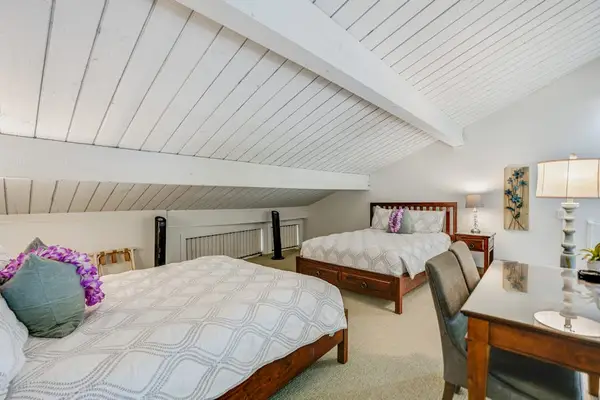 Bright loft bedroom provides comfortable sleeping space beneath vaulted ceilings