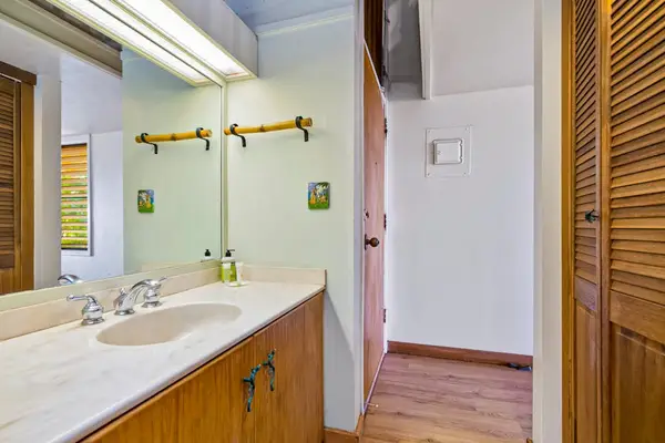 Spacious bathroom features dual sinks wood cabinetry and tiled surfaces