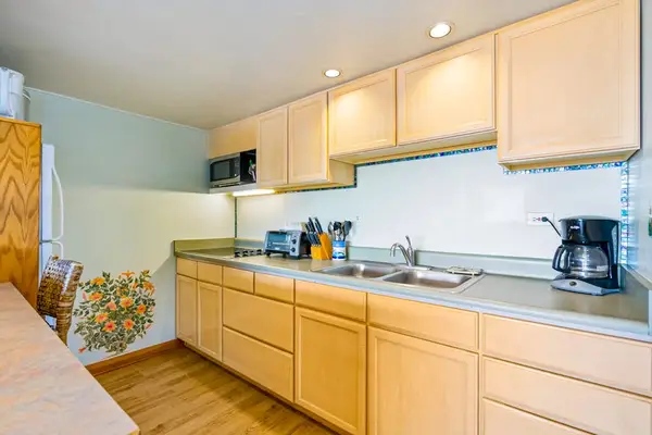 Light-filled kitchen presents warm cabinetry counters and practical meal preparation