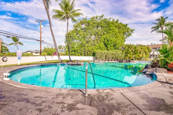 Sparkling Outdoor Swimming Pool surrounded by Palm Trees & Lush Greenery