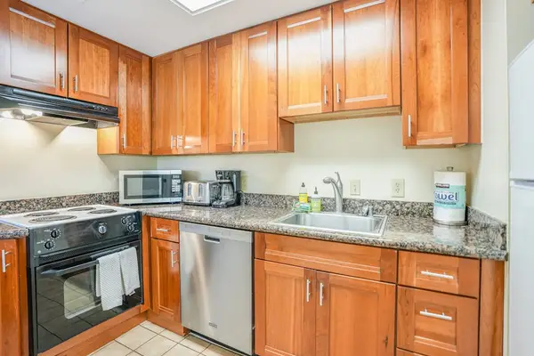 Well-equipped kitchen includes wooden cabinets, appliances, granite counters, and breakfast seating