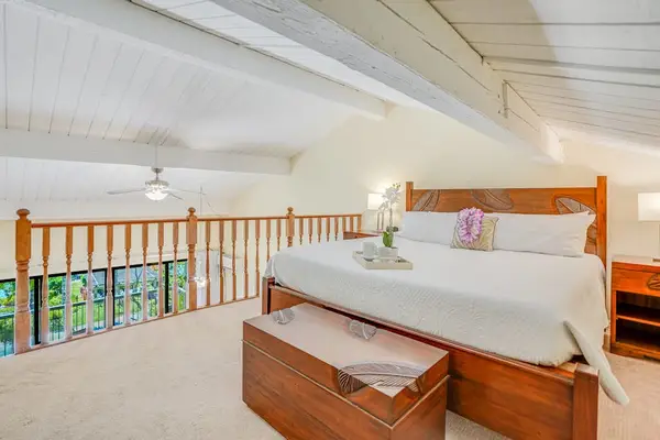 Loft bedroom features comfortable bedding, wooden accents, and balcony access