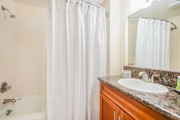 Bathroom includes glass shower, granite vanity, and bright overhead lighting