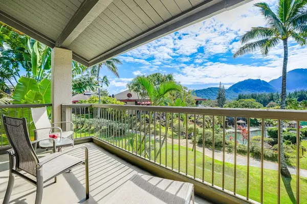 Balcony seating overlooks tropical gardens, resort grounds, and distant mountains