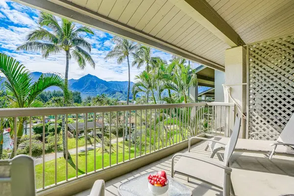 Covered balcony overlooks tropical gardens, swaying palms, and mountain scenery