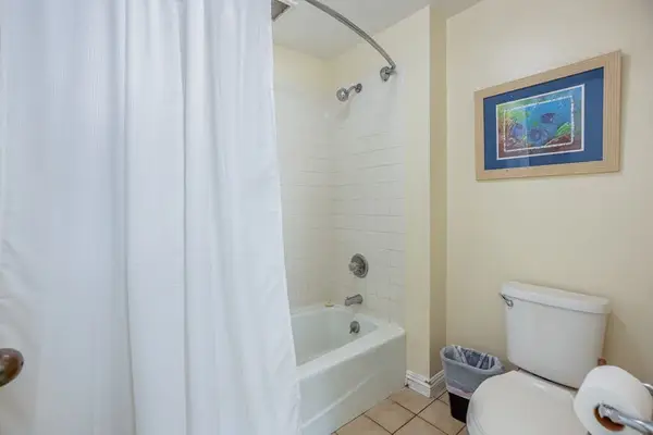 Bathroom includes bathtub, shower curtain, toilet, and colorful wall artwork