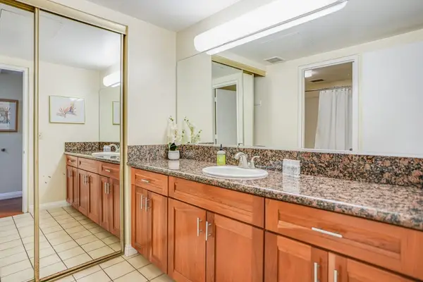 Bathroom vanity features double sinks, mirrored storage, and granite countertops