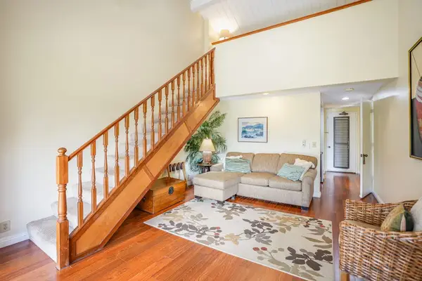 Spacious living area highlights hardwood floors, staircase, and inviting decor