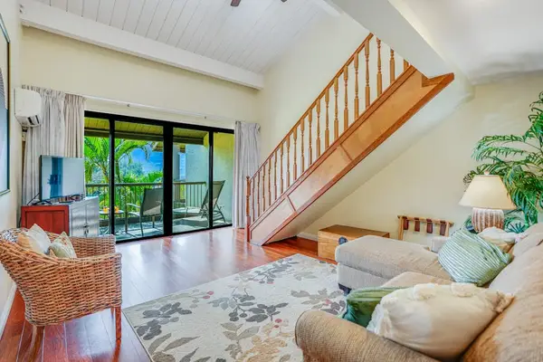 Open living room features staircase, balcony doors, and comfortable seating