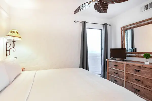 Primary Bedroom Suite featuring Wooden Dresser, Flat-Screen TV & Balcony Access