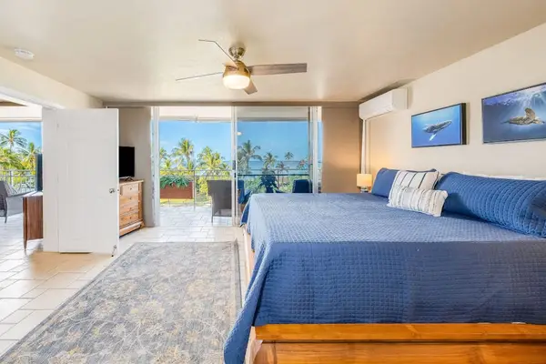Bright master bedroom with king bed, ceiling fan, and lanai access