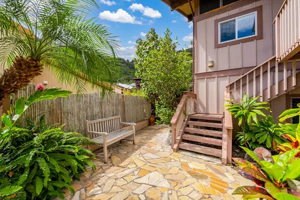 Welcome to a charming home entrance surrounded by tropical greenery