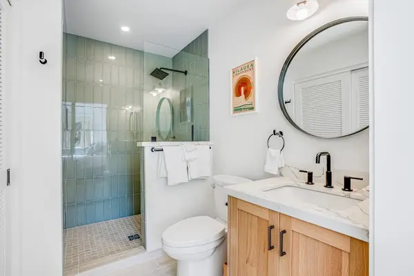 Stylish Ensuite Bathroom with Modern Vanity, Round Mirror & Tiled Walk-In Shower