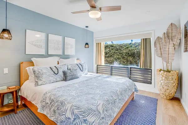 Coastal Primary Bedroom Accentuated by Soft Blue Wall, King Bed & Scenic Window Views