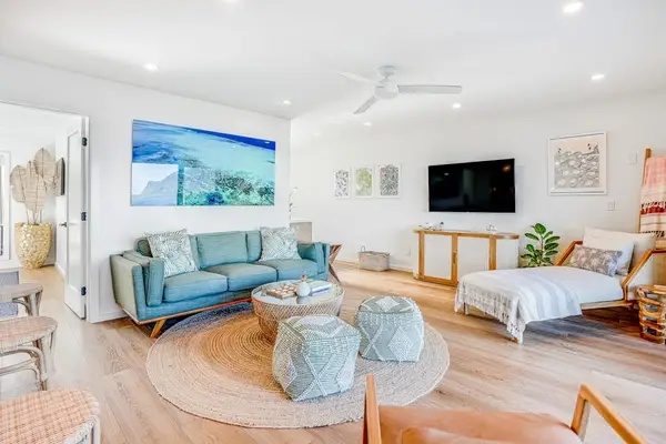 Spacious Living Room Setup with Sectional Sofa, Woven Poufs & Coastal Art