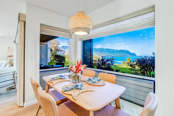 Coastal Dining Table Set for Four framed by Large Windows with Ocean & Mountain Views