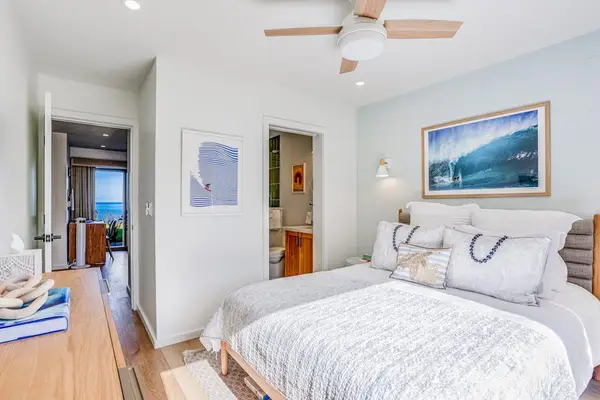 Cozy Bedroom Suite featuring Plush Bedding, Ceiling Fan & Ensuite Bathroom View