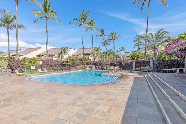 Tranquil blue water shimmers beside lush gardens and resort loungers