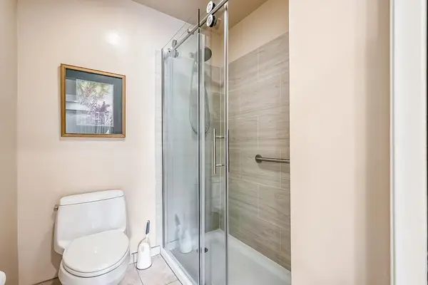 Full bathroom features glass shower enclosure toilet and wall art