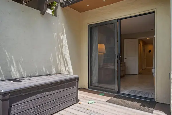 Patio bench sits beside sliding doors opening into condo interior
