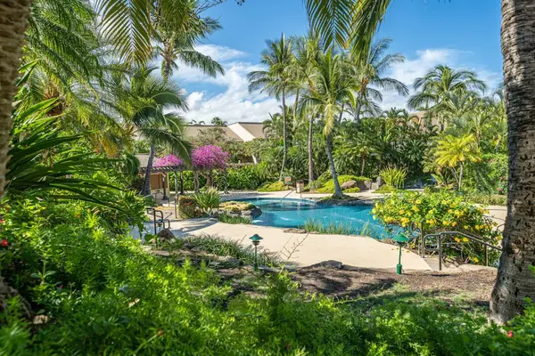 Lush courtyard entrance frames the condo with vibrant tropical landscaping