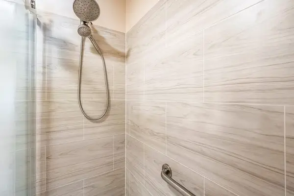 Glass shower features handheld fixture textured walls and tiled interior