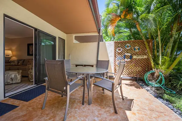Patio seating area overlooks landscaping beside the condo’s glass doors