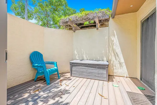 Sunny patio features comfortable chairs deck seating and garden walls