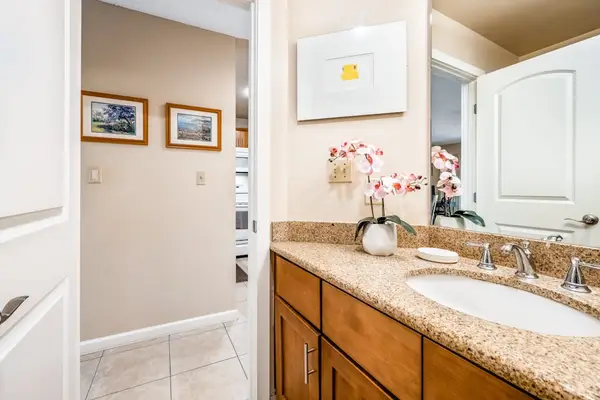 Bathroom vanity area features dual sinks mirrors and hallway access