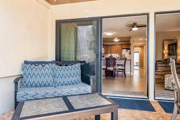 Patio features cushioned seating beside sliding doors and garden views