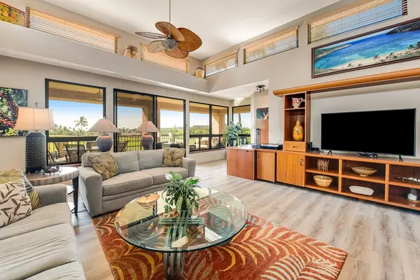 Living room features sofas, television, ceiling fan, artwork, and windows