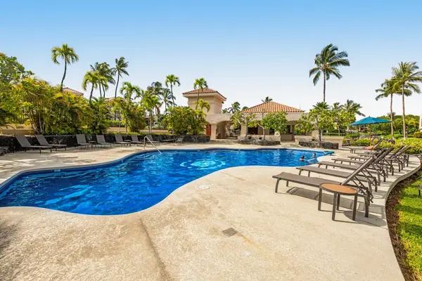 Poolside area features loungers, palms, water, pathways, and resort buildings