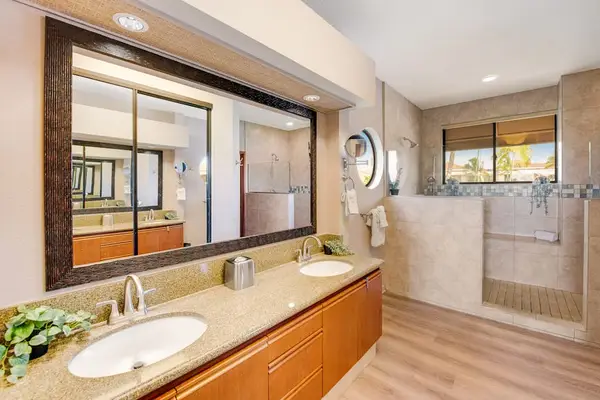 Bathroom vanity features double sinks, mirrors, lighting, counters, and storage