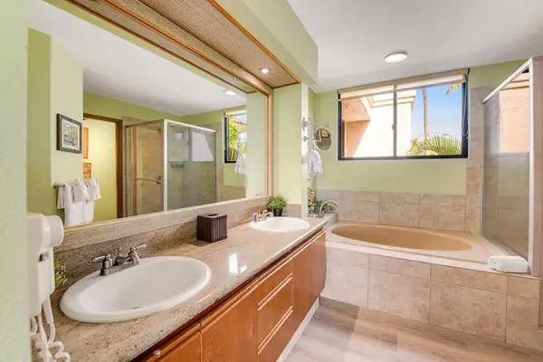 Ensuite bathroom includes soaking tub, vanity, mirrors, lighting, and tilework