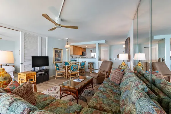 Living room with sofa bed, flat screen tv and rays of natural light streaming in from the lanai.