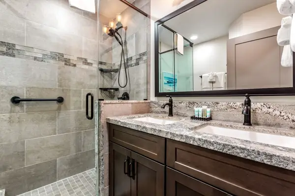 Newly remodeled master bath with two sinks and a spacious tiled walk-in shower.