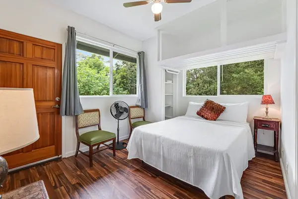 Master bedroom with queen bed and large windows.
