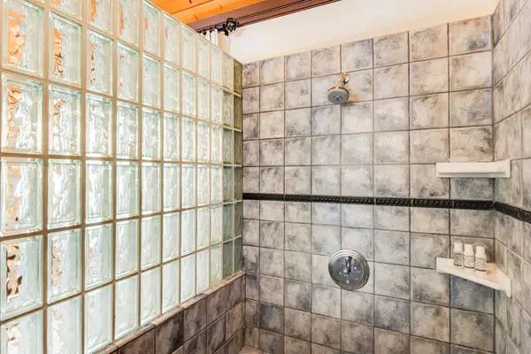 Spacious Walk-In Shower with Custom Stone Tile & Built-In Shelving