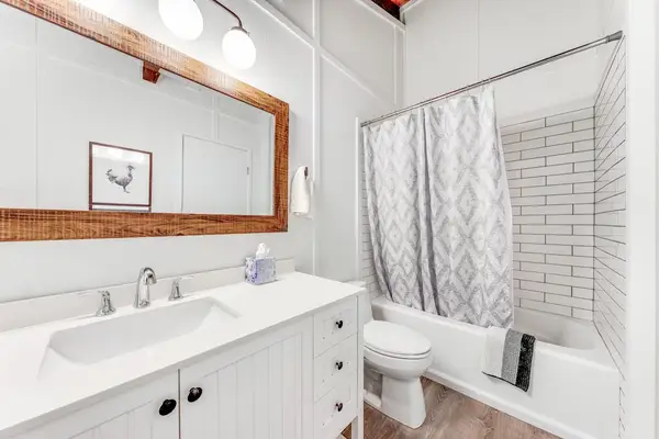 Fresh white bathroom pairs broad vanity tub shower and mirror