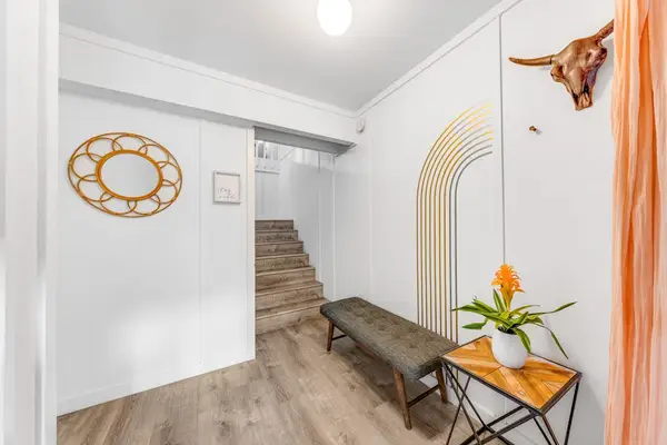 Entry hall leads upstairs past island inspired artwork and seating