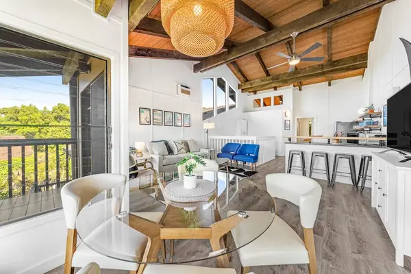 Round glass dining table catches daylight beside balcony and kitchen