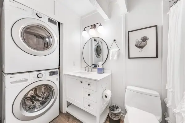 Washer and dryer share bright bath with vanity and storage